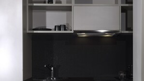 Cozinha moderna com armários brancos, bancada preta e exaustor de aço inoxidável.