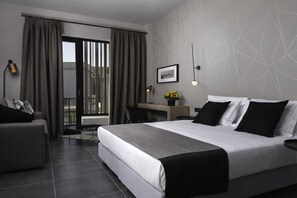 Camera d'albergo moderna con un letto grande, una scrivania, una sedia e vista all'esterno tramite una porta scorrevole.