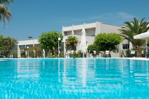 Relax by the serene pool surrounded by lush greenery and palm trees.