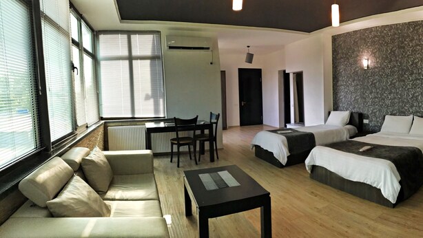 A modern hotel room with three beds, a sofa, a small table, and a desk. - Hotel Continental (Kutaisi)