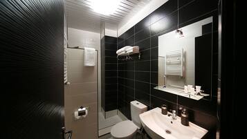 A modern bathroom with a shower, toilet, sink, and a mirror.