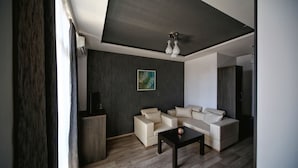 A modern living room with a sectional sofa, a coffee table, and a painting on the wall. - Hotel Continental (Kutaisi)