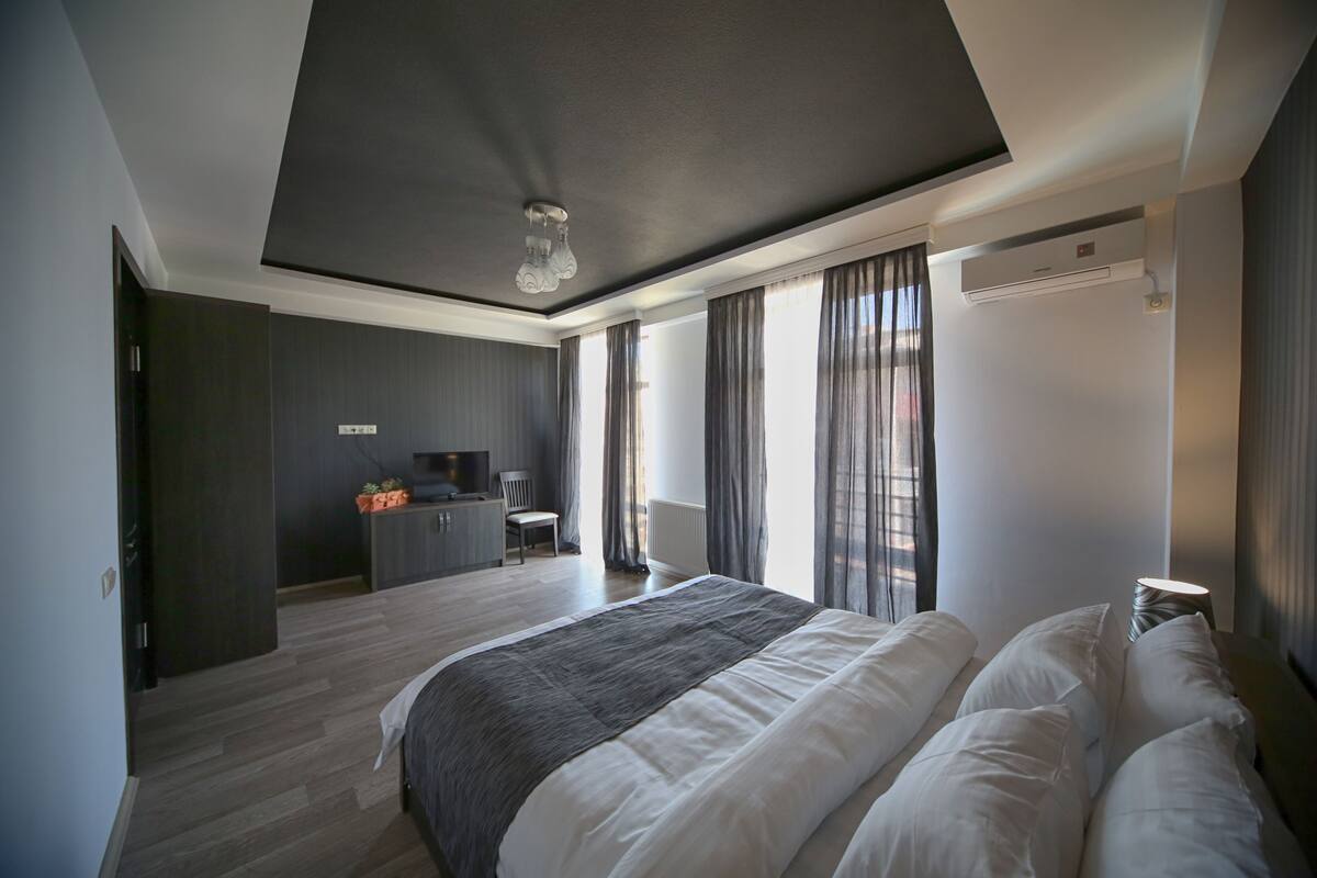 A modern bedroom with a large bed, a desk, and a chair.