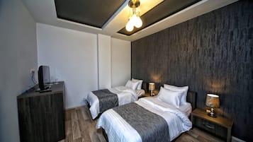 A modern hotel room with two beds, a wooden dresser, a flat-screen TV, and a ceiling light fixture.