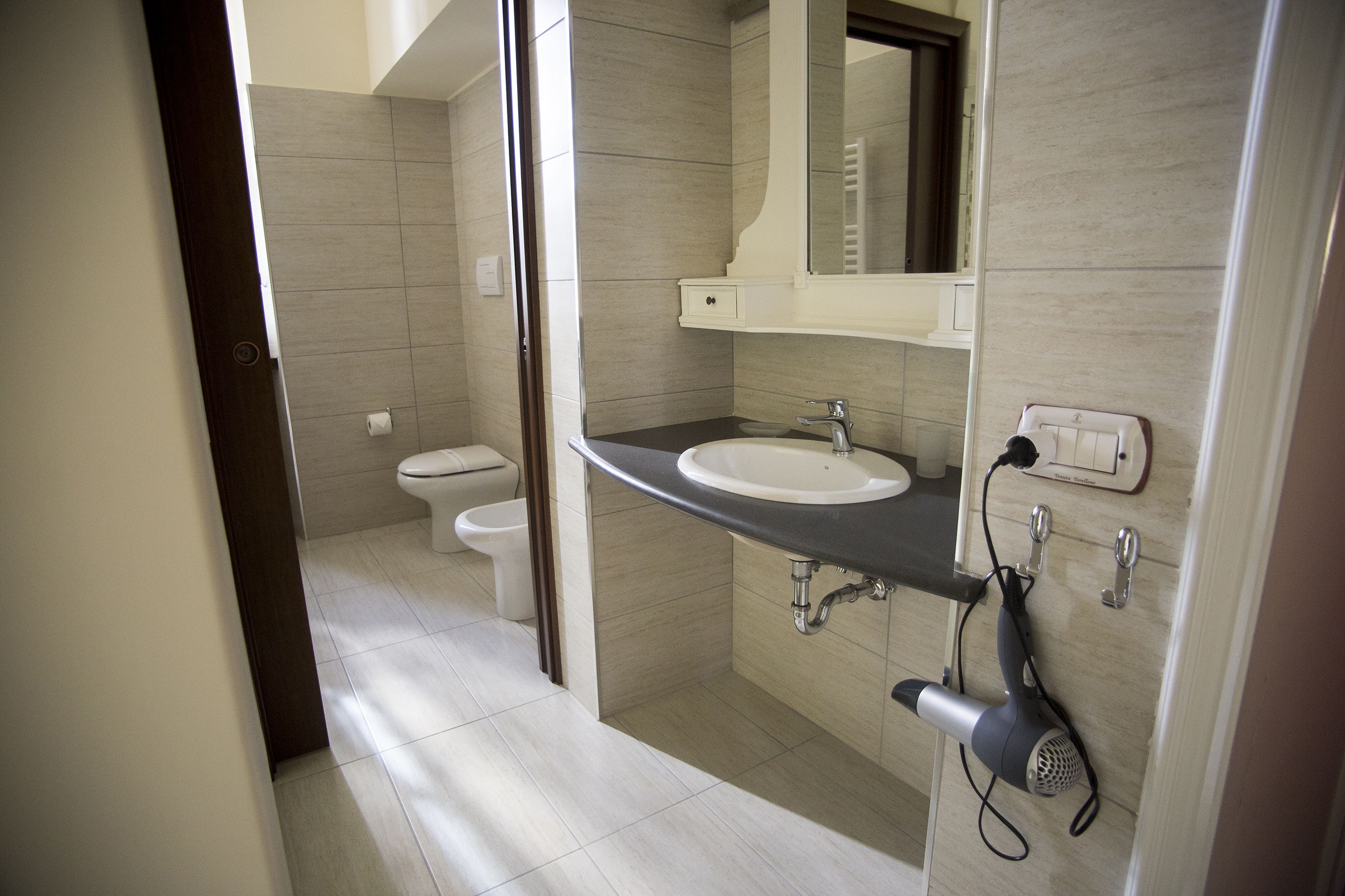 A modern bathroom with a sink, mirror, and hairdryer.