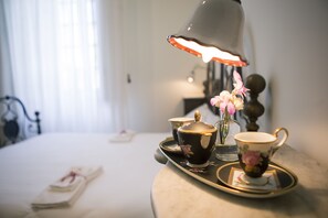 A tray with a teapot, cups, and a vase with flowers on a table in a room with a bed and curtains. - Tenuta Torellone (San Potito Sannitico)