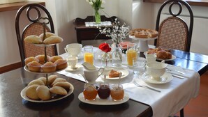 A breakfast table set with pastries, fruits, and beverages.