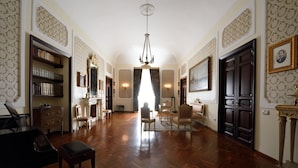 A spacious room with a grand piano, wooden flooring, and a chandelier.