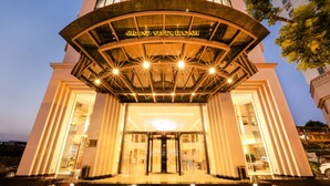 A grand entrance with a large glass door, a central light fixture, and a sign above the door. - Grand Vista Hanoi (Hanoi)
