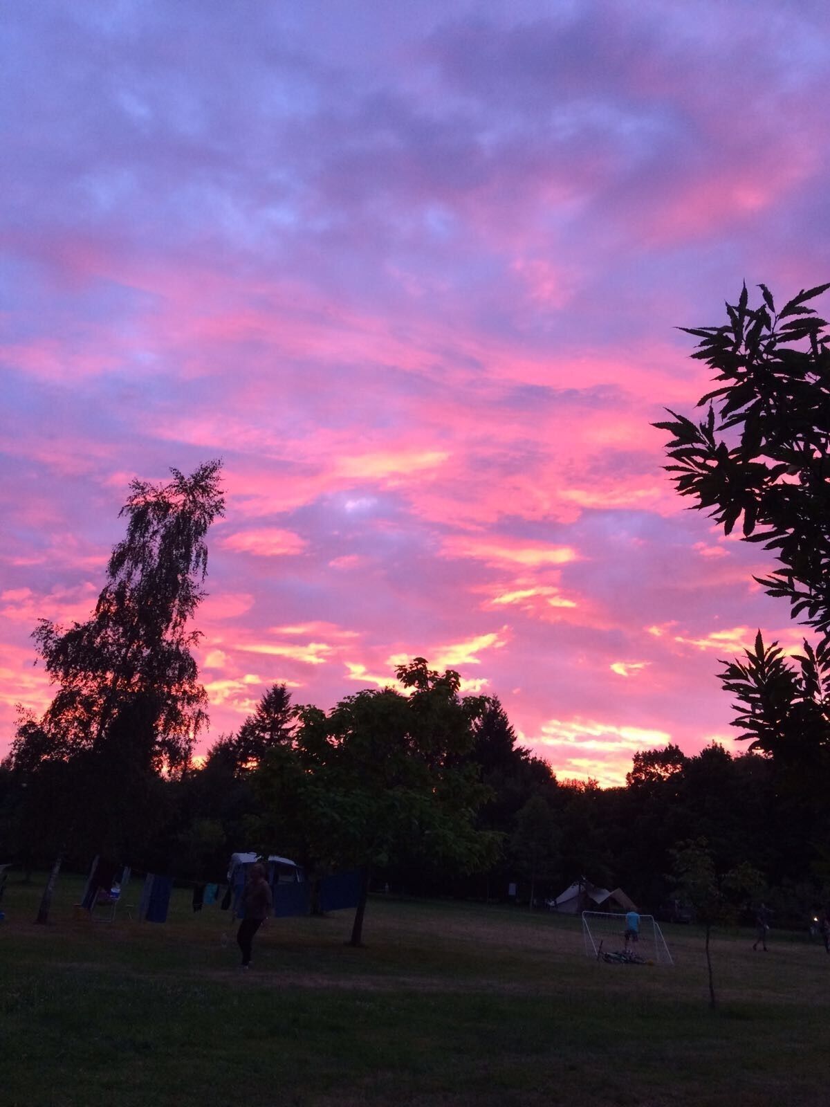 Un atardecer sobre un parque con árboles y un campo de fútbol.
