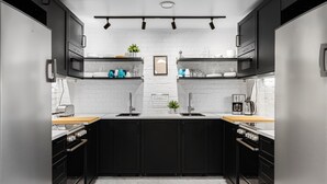 A modern kitchen with black cabinets, a white countertop, and a stainless steel refrigerator. - Kallhällsbaden Vandrarhem - Hostel (Jarfalla)