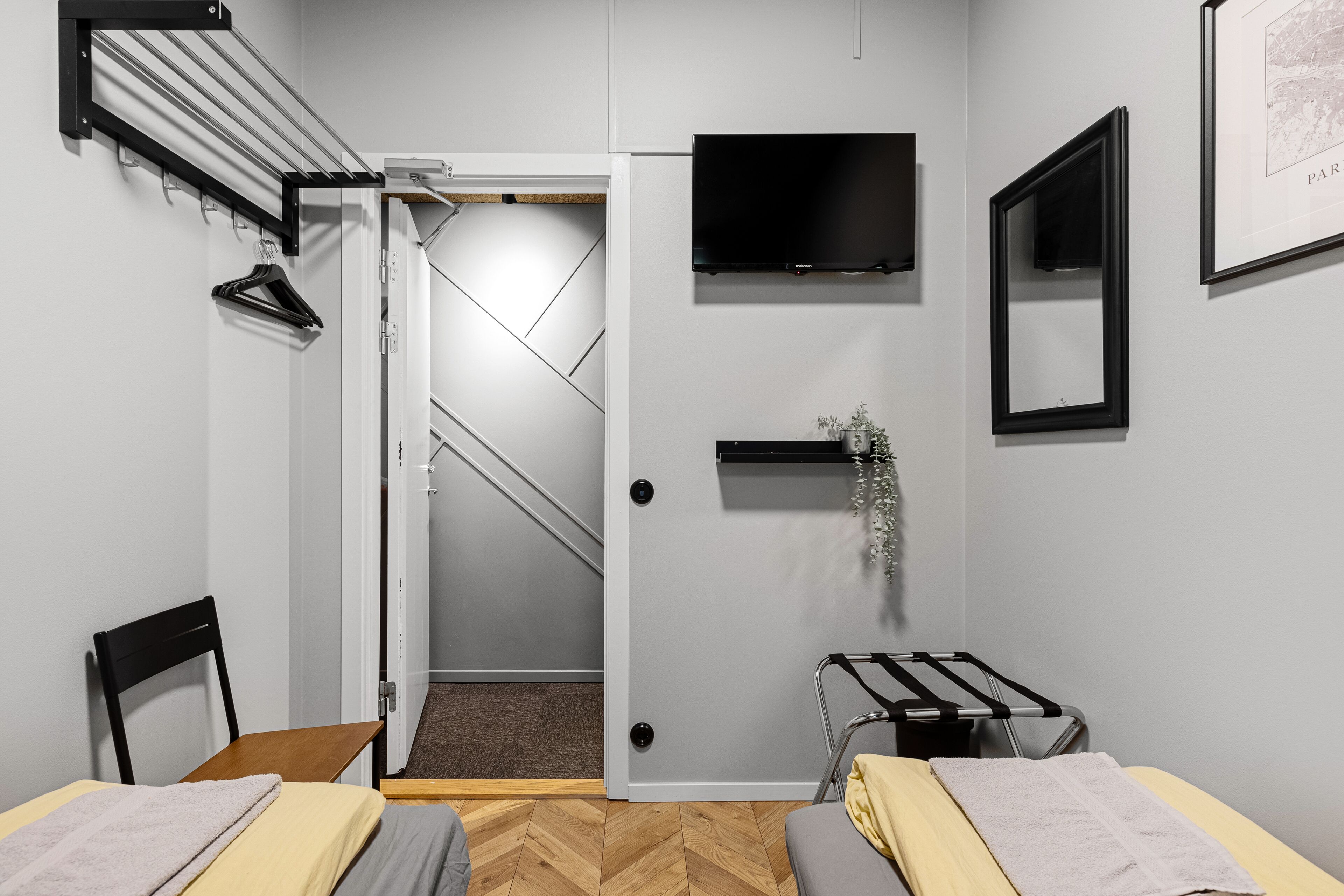 A modern hotel room with a bed, a chair, a TV, and a door leading to a staircase.