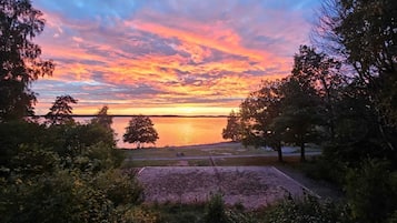 Una vista del atardecer sobre un lago tranquilo, con árboles en primer plano.