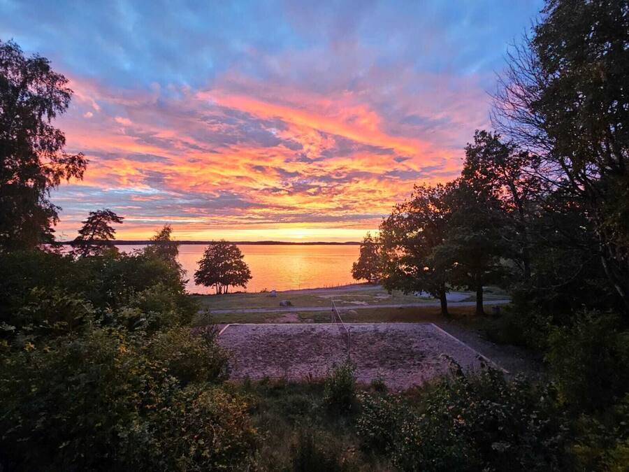 Una vista del atardecer sobre un lago tranquilo, con árboles en primer plano.