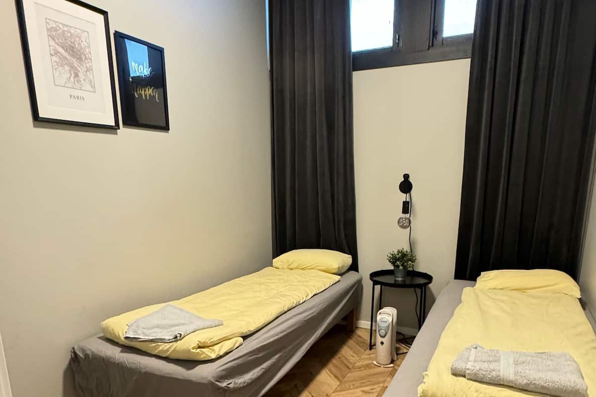 Et lille, pænt værelse med to senge, et lille bord og en potteplante.