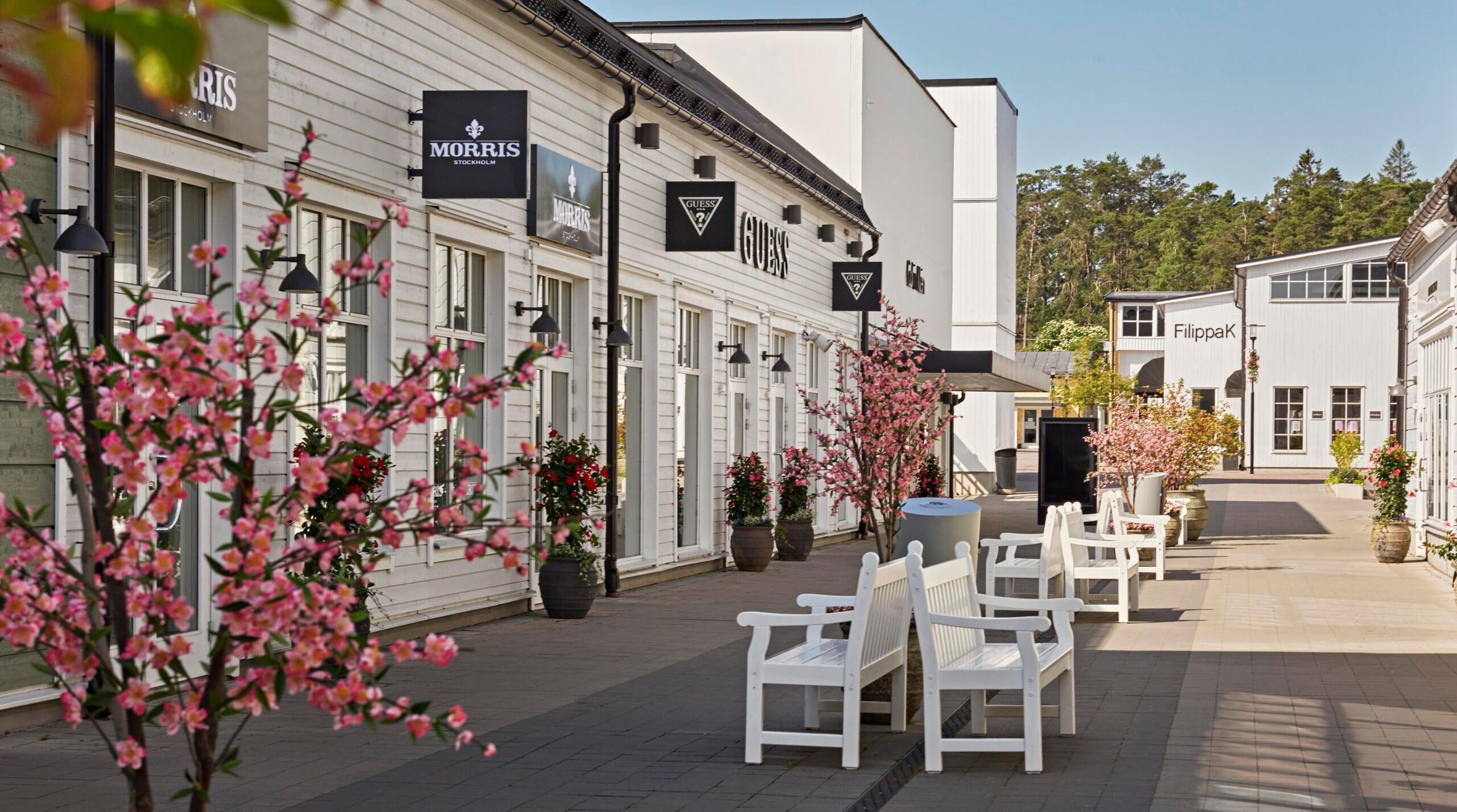 A row of white benches outside a building with 'MORRIS STOCKHOLM' signage.