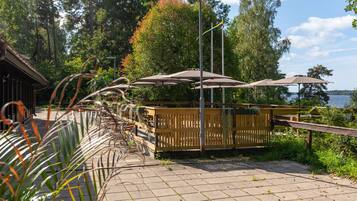 A wooden deck with umbrellas, a wooden fence, and a view of a lake.