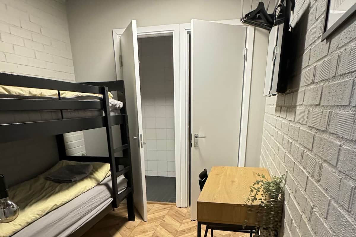 Et lille, kompakt rum med køjeseng, et træbord og en radiator.