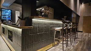 A modern bar area with a high counter, bar stools, and a television screen. - Kallhällsbaden Vandrarhem - Hostel (Jarfalla)