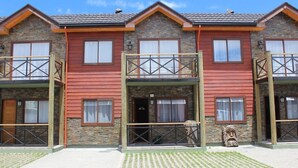 A row of two-story buildings with stone facades and red wooden siding, featuring balconies and a central entrance. - New apartment, 1A center of Villarrica (Villarrica, Araucania)