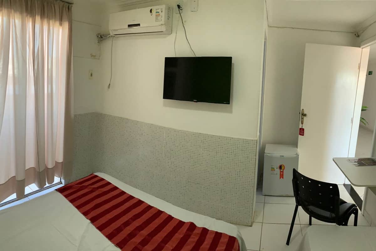 A hotel room with a bed, a TV, a small table, and a chair.