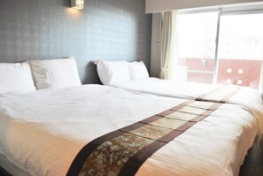 Habitación de hotel con dos camas, un ventanal grande y vista a un edificio.