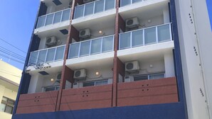 A multi-story hotel with balconies, air conditioning units, and a ground-level entrance. - Ten Point Hotel (Naha)