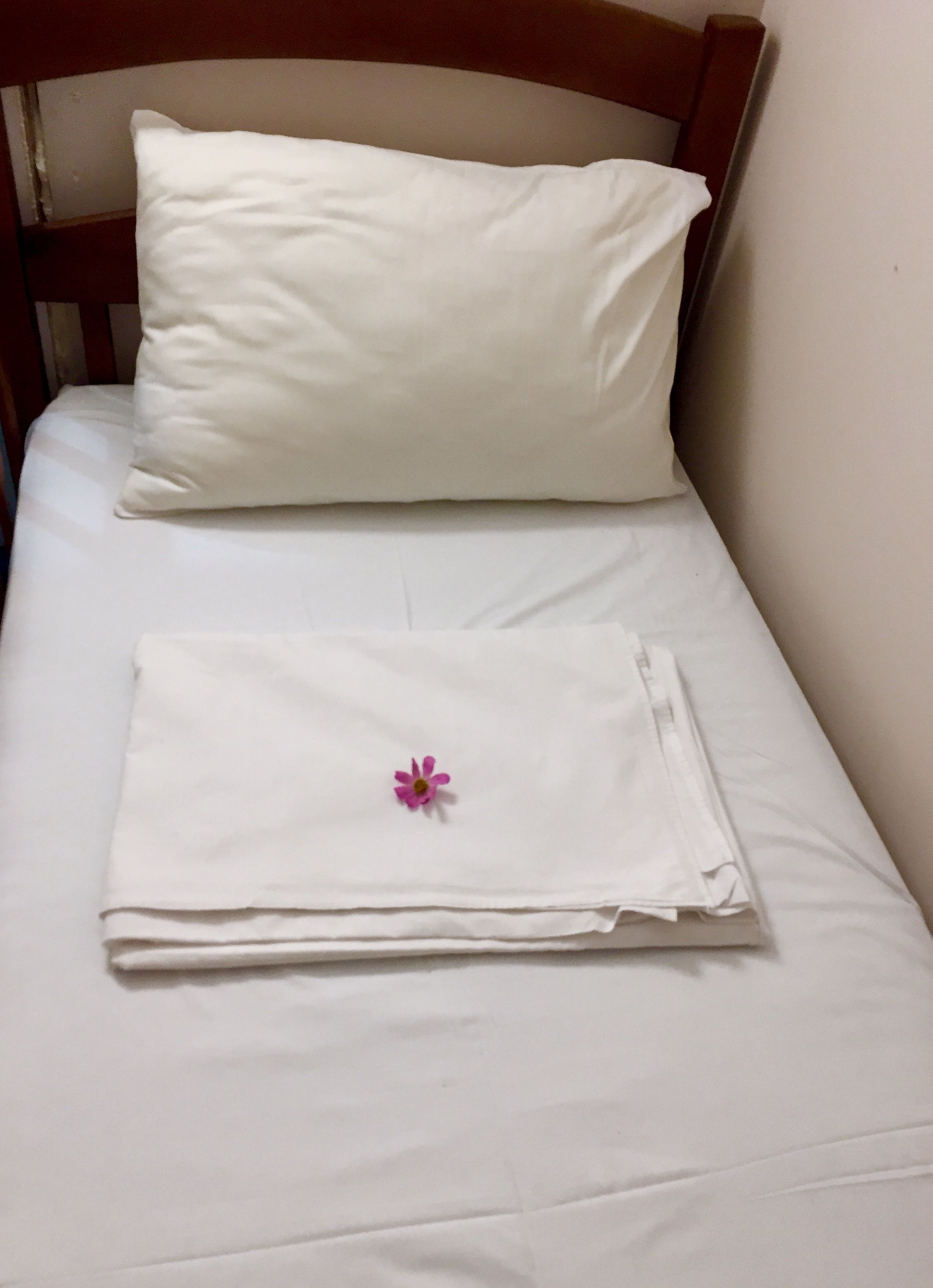 Un letto rifatto con un cuscino bianco e un lenzuolo bianco ripiegato.