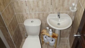 A small bathroom with a toilet, sink, and a mirror. - Edificio Angelo (Cartago)