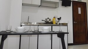 A kitchen with white cabinets, a black countertop, a stove, a sink, and a door marked "SALIDA DE EMERGENCIA". - Edificio Angelo (Cartago)