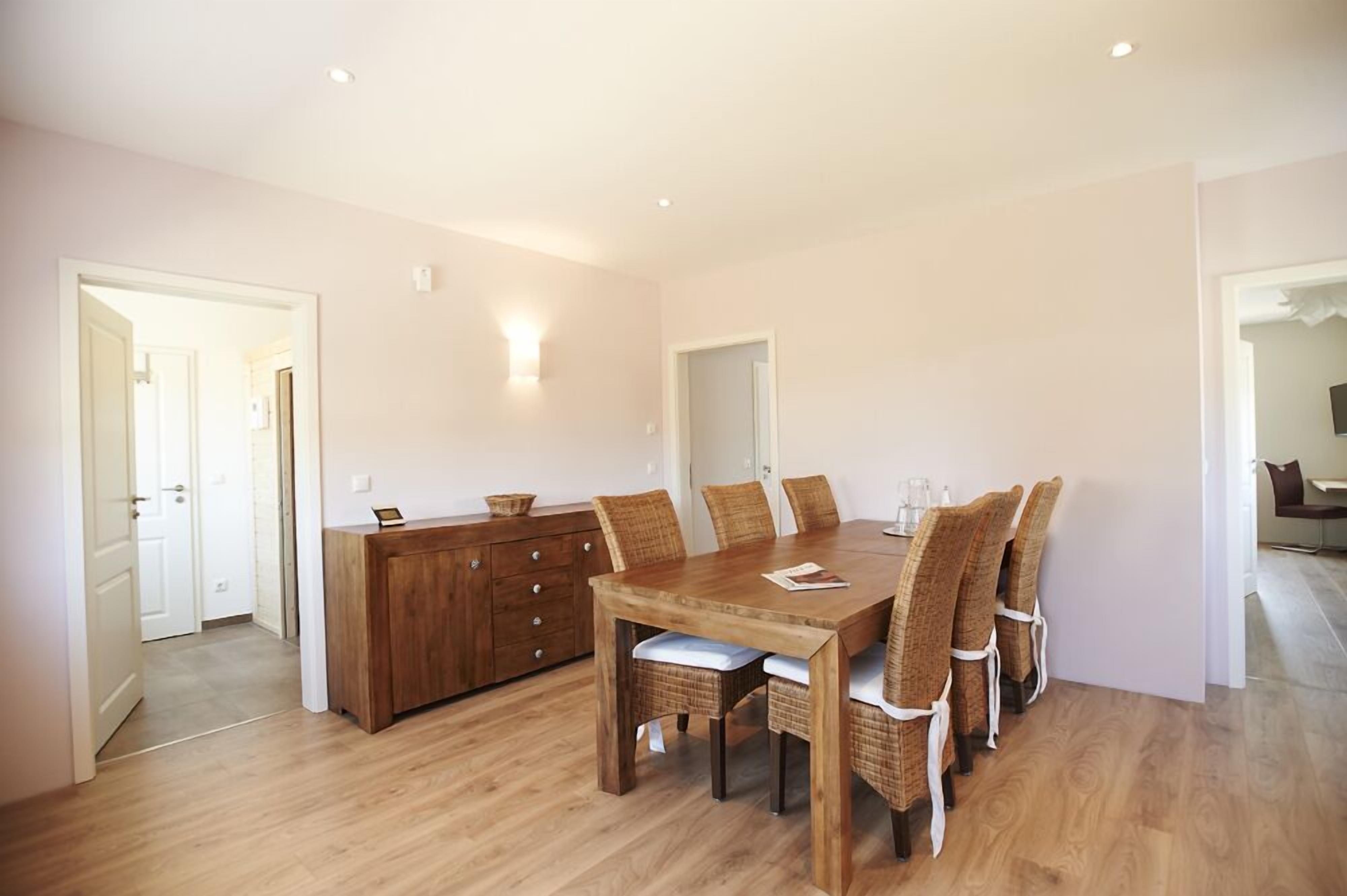 Ein Essbereich mit Holztisch und Stühlen, einem Holzschrank und einem Spiegel an der Wand.