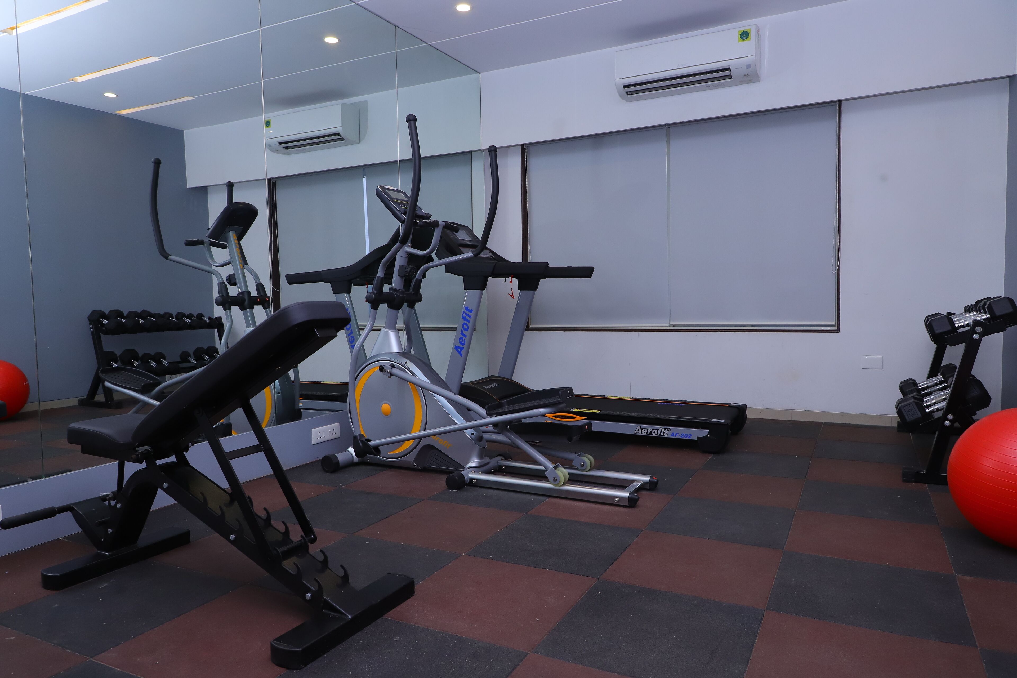 A gym with various exercise equipment, including treadmills, a stationary bike, and dumbbells.
