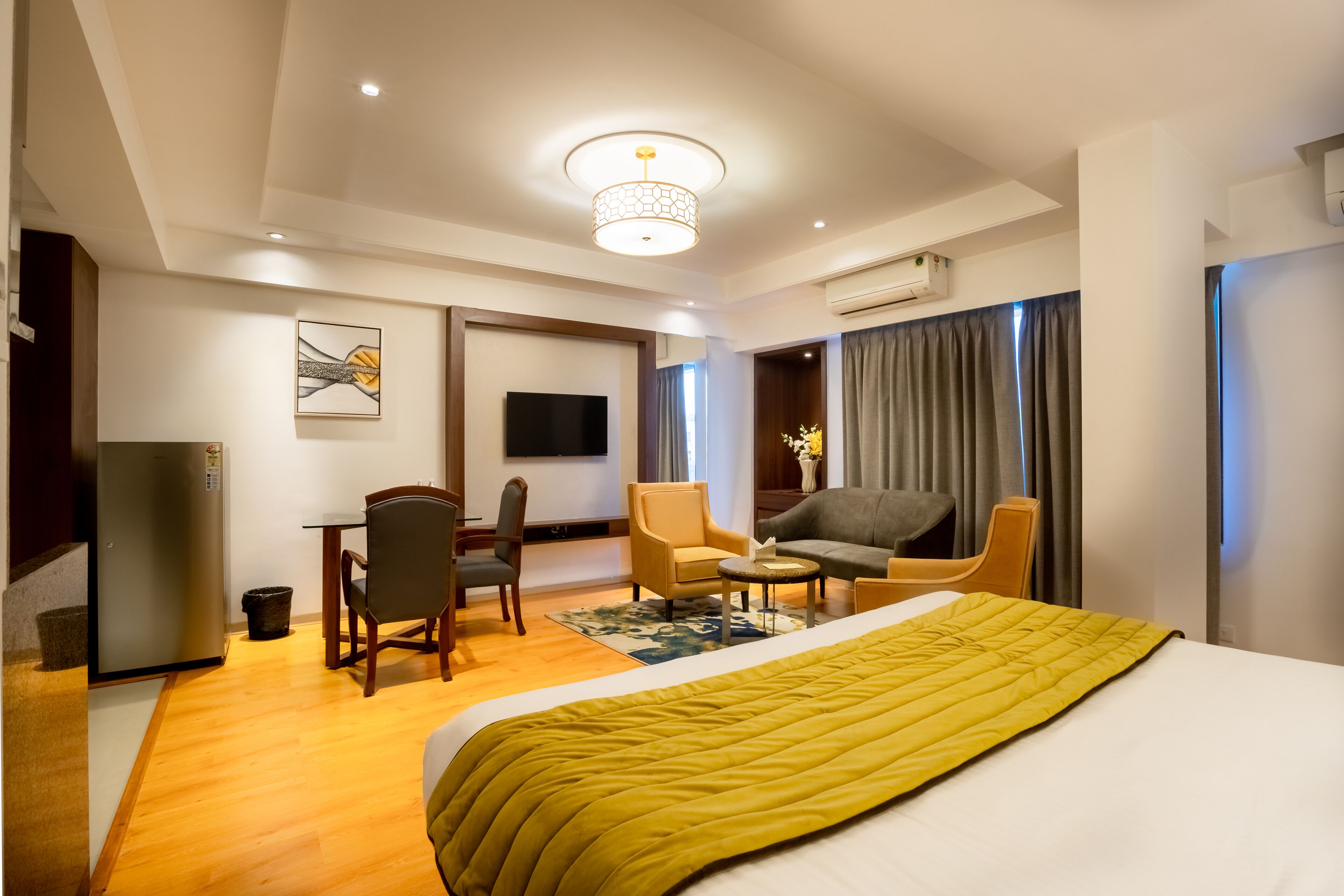 A hotel room with a bed, a desk, a chair, a sofa, and a television.