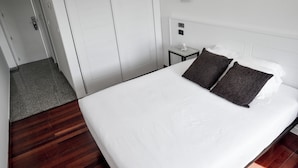 Habitación de hotel con una cama grande, una mesita de noche y una puerta con pomo.