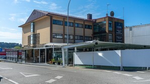 Un edificio moderno con una zona de entrada cubierta, ventanas amplias y un cartel publicitando papas fritas.