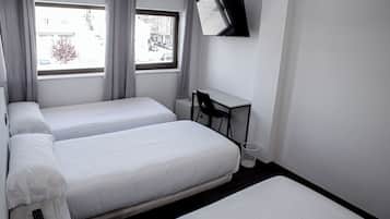 A hotel room with two beds, a desk, a chair, and a TV mounted on the wall.