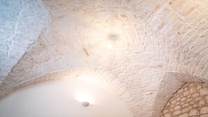 Quarto com teto de pedra, armário de madeira e parede de pedra com uma pequena prateleira.