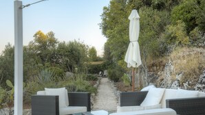 An outdoor seating area with wicker furniture and a white umbrella. - La Lamia 1864 Ostuni by Typney (Ostuni)