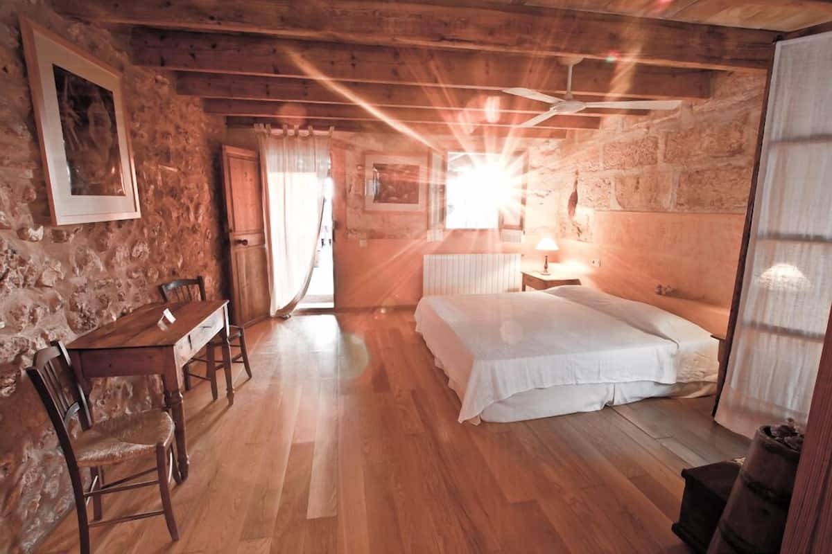 Una habitación rústica con una mesa de comedor de madera, una cama y una pared de piedra.