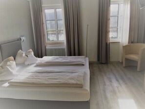 A hotel room with a bed, a chair, and a window with curtains. - Landhotel Steffen (Lieser)