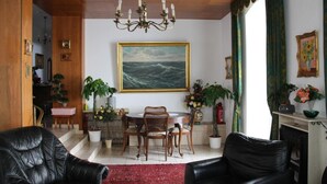 A dining area with a round table, chairs, and a chandelier. There are potted plants and a painting on the wall. - Hotel Humboldt (Bad Kissingen)