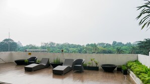 A rooftop terrace with lounge chairs and planters, overlooking a lush green landscape. - Best Price 2BR at Taman Melati Margonda Apartment (Depok)