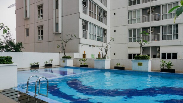 An indoor swimming pool with clear water, surrounded by a building with multiple balconies and potted plants. - Best Price 2BR at Taman Melati Margonda Apartment (Depok)