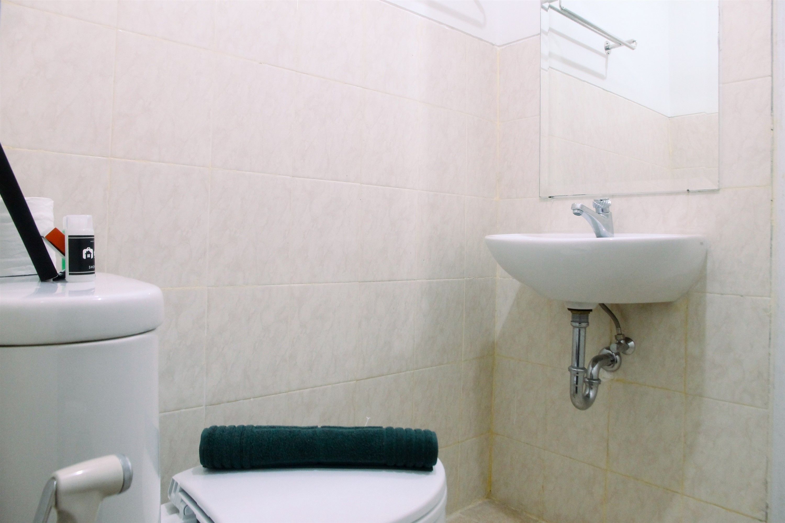 A bathroom with a toilet, sink, and a towel on the floor.