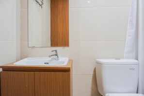 Une salle de bain avec un meuble-lavabo en bois, un lavabo blanc et des toilettes.