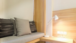 Una stanza moderna con una panca in legno, una scrivania bianca e una lampada.