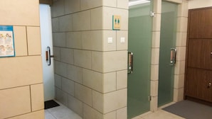 Un bagno con pareti piastrellate, una porta in vetro e una porta in legno.