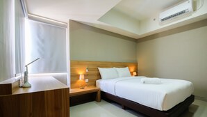 A modern hotel room with a wooden headboard, a large bed with white linens, bedside lamps, a wooden nightstand, and an air conditioning unit on the ceiling. - Best Location 1BR Mustika Golf Apartment (Cikarang)