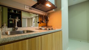 A kitchen with a stainless steel sink, wooden cabinets, and a granite countertop. - Best Location 1BR Mustika Golf Apartment (Cikarang)