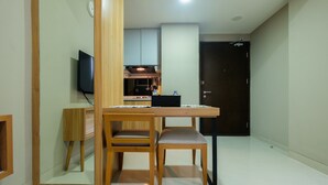 A compact living space with a dining area, kitchenette, and a dark door. - Best Location 1BR Mustika Golf Apartment (Cikarang)